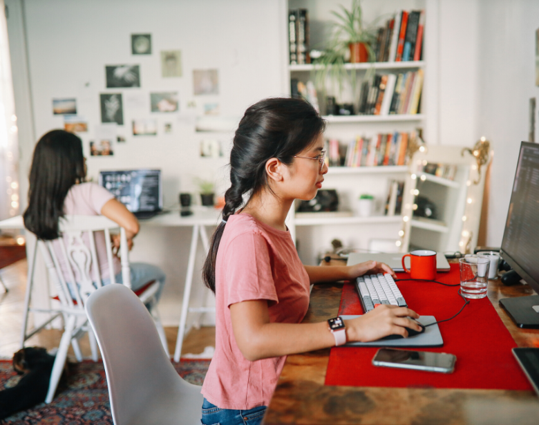 Two roommates sitting together in a home office.