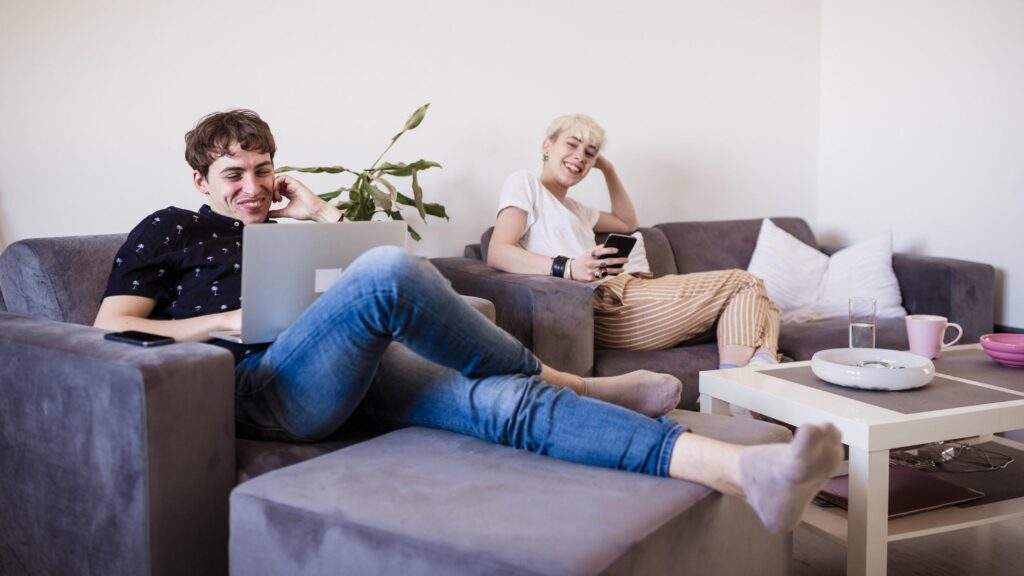 man and woman laughing together sitting on a grey couch